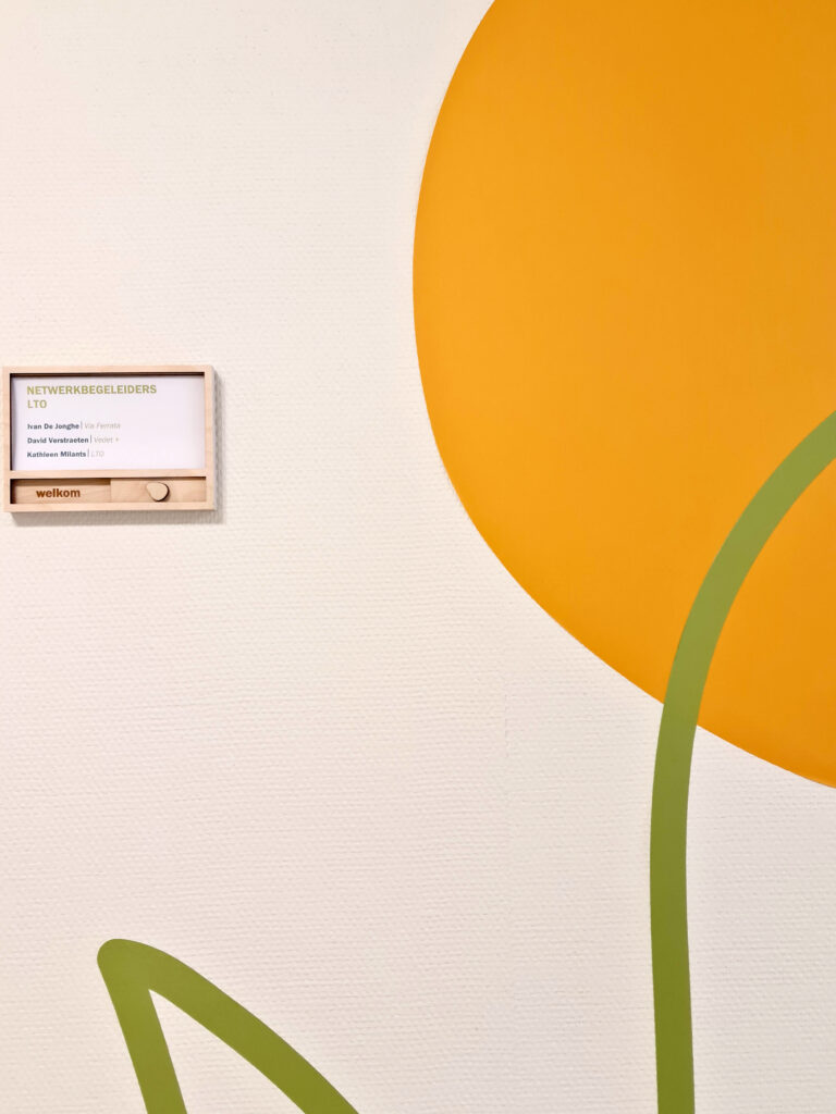 Een naambordje naast een muursticker in oranje en groen